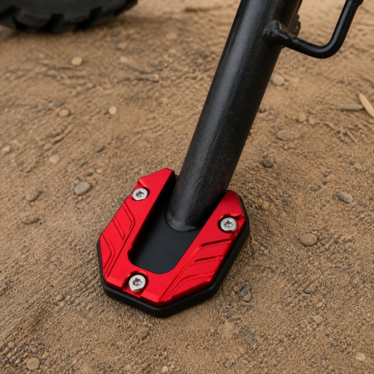 Red CNC kickstand pad on a motorcycle side stand on firm dirt